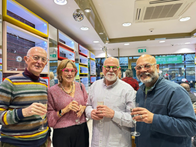 4 happy people wearing brightly coloured glasses holding champagne glasses at a party