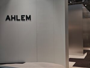 A minimalist exhibition booth with the brand name “AHLEM” in bold black letters on a pale wall at SILMO Paris 2025.